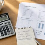 Kalkulator, notatki i dokumenty finansowe na stole w naturalnym świetle
